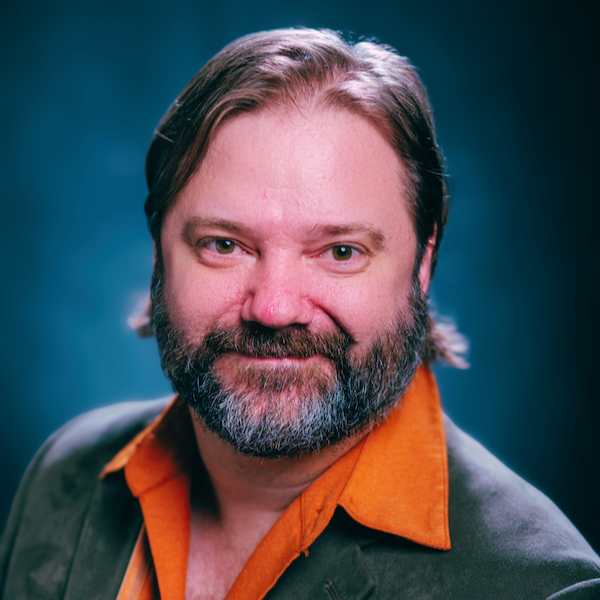 Jesse Allison headshot. He is wearing a suit jacket on a dark blue background.
