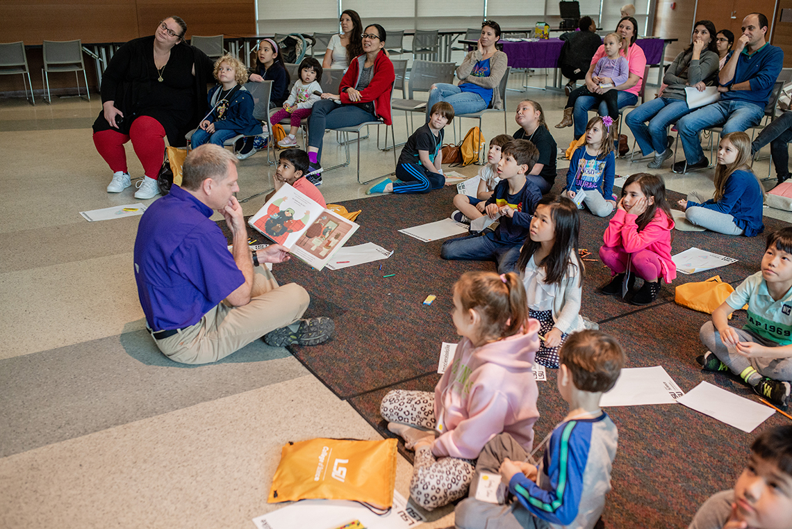 Dr. Kyle Harms reads a childrens' book to STEM Story Time participants.
